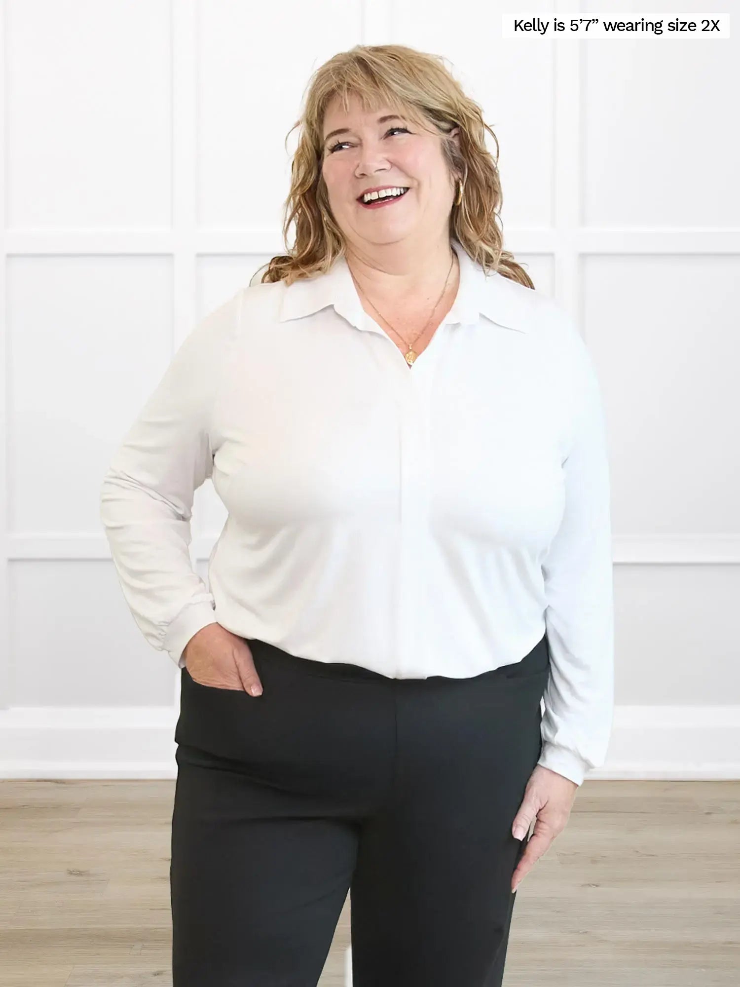Woman wearing a white blouse and black pants against a white background 