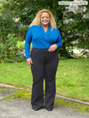 Miik model Carley (five feet two, xxlarge) wearing Miik's Laney mi-rise flare pant in graphite along with a peacock long sleeve top