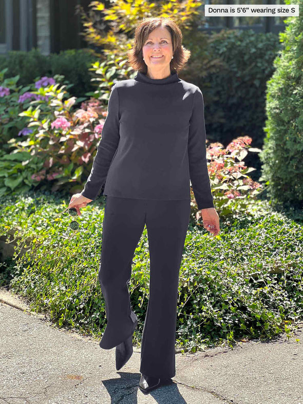 Miik founder Donna (five feet six, small) smiling wearing Miik's Laney mid-rise flare pant in graphite with a same colour and fabric long sleeve Breda top