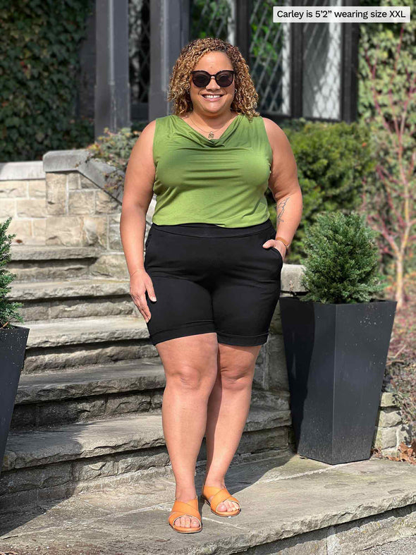 Miik model Carley (5'2", xxlarge) smiling wearing Miik's Leland everyday dressy short in black with a top in green moss