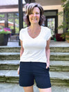 Miik founder Donna (5'6", small) smiling wearing Miik's Leland everyday dressy short in navy with a v-neck tee in white
