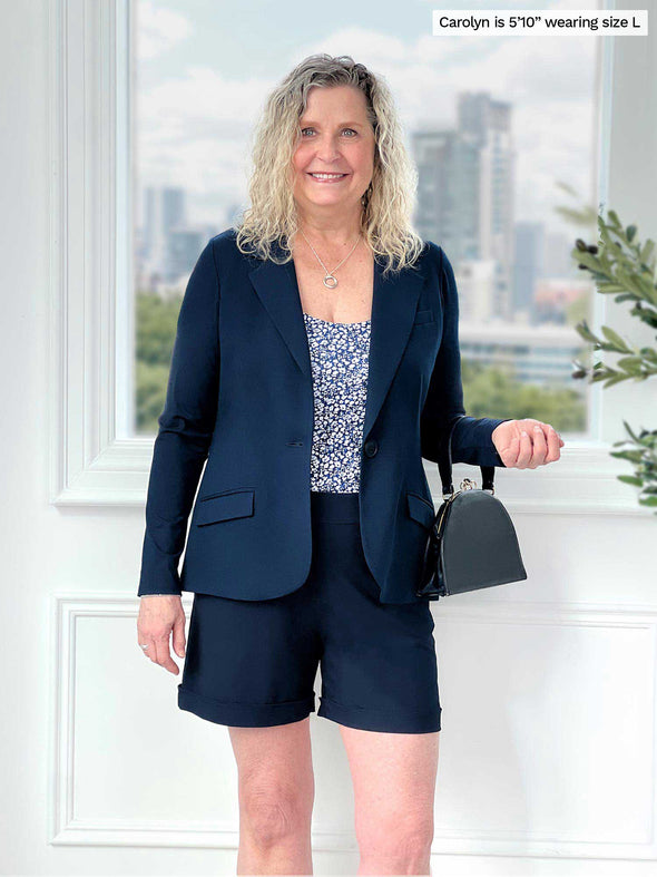 Miik model Carolyn (5'10, large) smiling wearing Miik's Leland everyday dressy short in navy along with a blazer in the same colour and a printed tee 