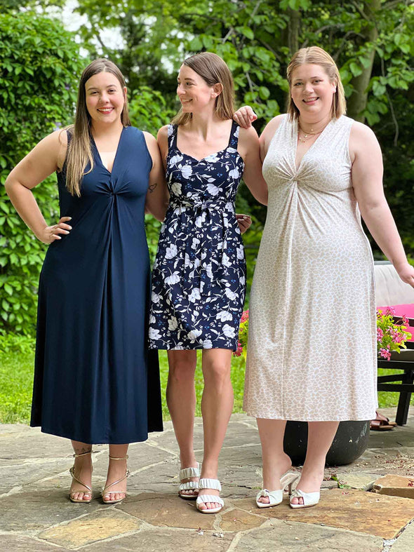 Miik models Christal, Jo and Bri standing next to each other, smiling and all wearing Miik styles. Christal is wearing Miik's Lina midi knot dress in navy, Jo is wearing Miik's Maryse reversivle sweetheart dress in blossom print and Bri is wearing Miik's Lina midi knot dress in cobblestone 