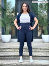 Miik model Yasmine (5'0", xsmall, petite) smiling wearing Miik's Lisa2 high waisted capri legging in navy with a cardigan in the same colour and a white tank