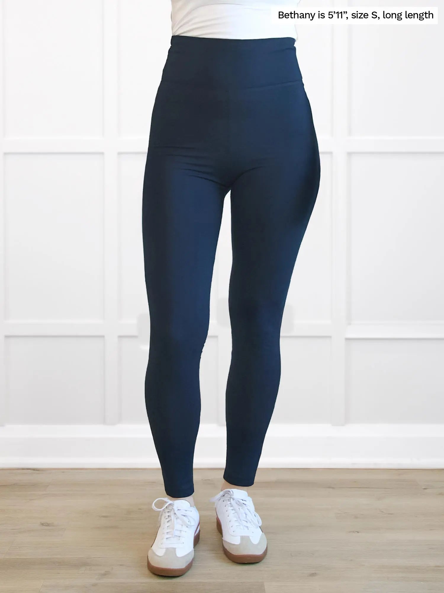 Person wearing navy leggings with a white background 