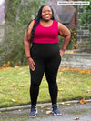 Miik model plus size Kimesha (5'8", 3x) smiling and looking up wearing Miik's Lisa2 high waisted legging in black with a bordeaux tank 