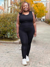 Miik model plus size Erica (5'8", 2x) smiling while wearing an all black outfit: Miik's Lisa2 high waisted legging and Alanis classic tank top 