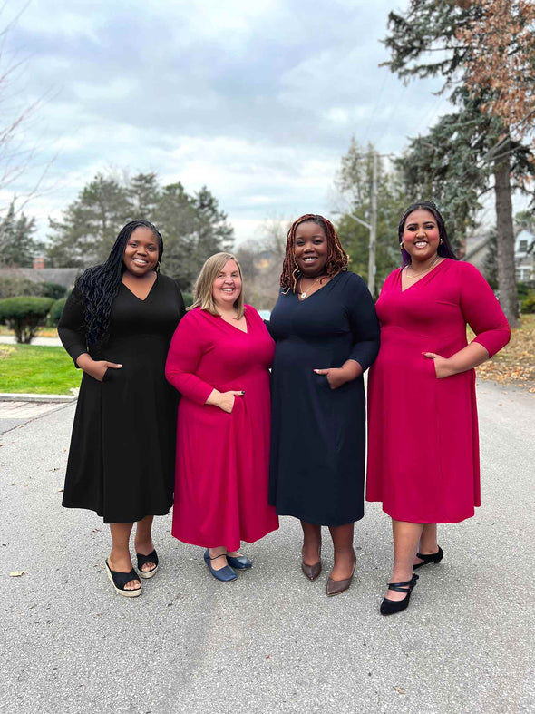 Miik models plus size Kimesha, Jennifer, Erica and Sureka standing next to each other smiling all wearing Miik's Lolly midi flounce dress with pockets in the colour available: black, bordeaux and navy