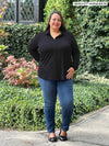 Miik model plus size Sarita (5'7", 2x) smiling wearing Miik's Lucia collared shirt in black with jean