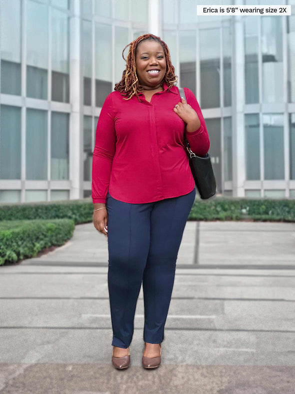 Miik model plus size Erica (5'8", 2x) smiling while standing in front of a building wearing a corporate outfit: Miik's Lucia collared shirt in bordeaux and Christal pant in navy