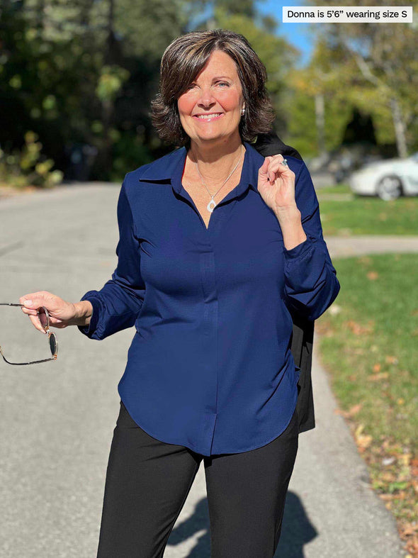 Miik founder Donna (5'6", small) smiling wearing Mik's Lucia collared shirt in ink blue with a black pant holding a sunglass 