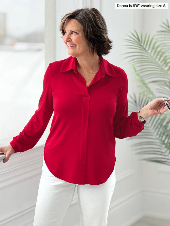 Miik founder Donna (5'6", small) smiling and looking away wearing Miik's Lucia collared shirt in poppy red with white jeans
