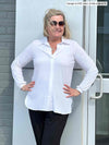 Miik model Carolyn (5"10', large) wearing Miik's Lucia collared shirt in white untucked over black pants.
