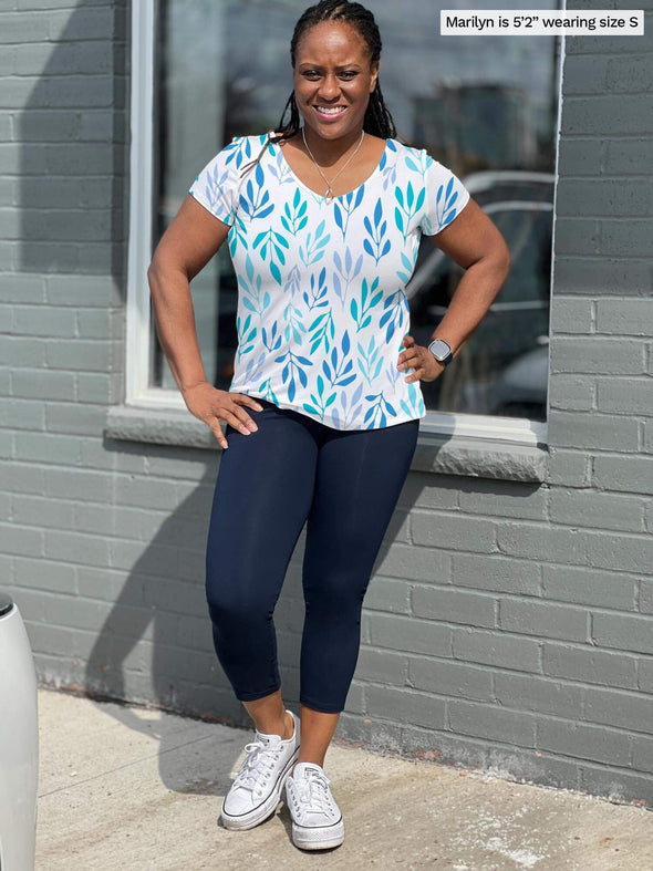 Woman smiling and standing in front of a brick wall wearing Miik's Lucy capri legging in navy with marianna t-shirt in ocean leaf print