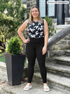 Miik model Christal (5'3", large) smiling wearing Miik's Lucy mid-rise legging in black with a printed tank 