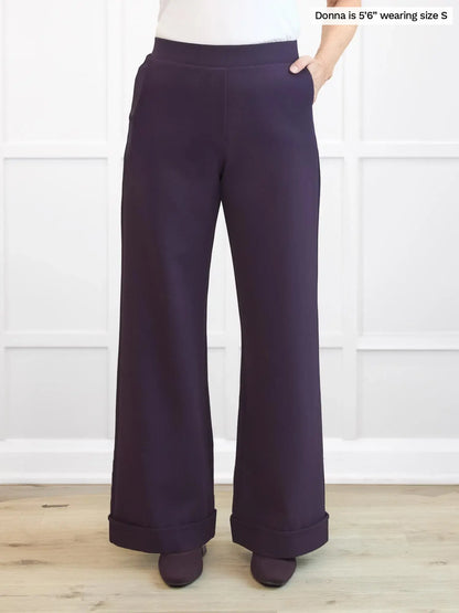 Purple wide-leg pants worn by a person on a white background 