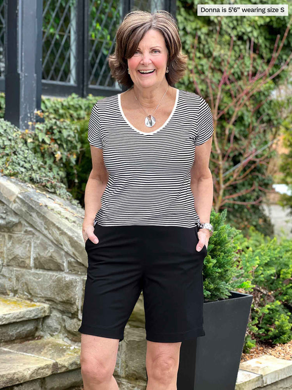 Miik founder Donna (5'6", small) smiling wearing Miik's Marianna reversible classic tee in mini stripe along with a black shorts 