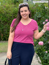 Miik model Christal (5'3". large) smiling wearing Miik's Marianna reversible classic tee in pretty in pink with a navy pant 