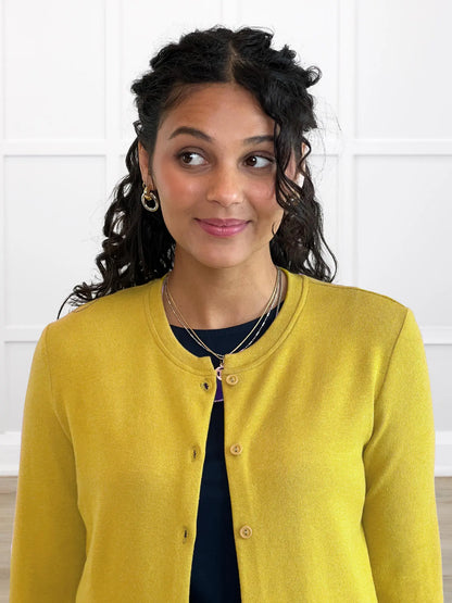 Woman wearing a yellow cardigan against a white background 