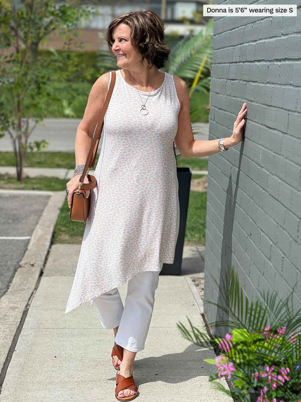 Miik founder Donna (five feet six, small) standing in a sidewalk looking away wearing a white jeans with Miik's Mariska asymmetrical tunic dress in cobblestone print