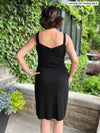 Miik founder Donna (five feet six, small) tanding with her back towards the camera showing the back of Miik's Maryse reversible sweetheart dress in black, when the scoop neckline is worn in the front and the sweetheart in the back