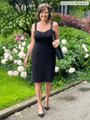 Miik founder Donna (five feet six, small) standing in front of a garden smiling wearing Miik's Maryse reversible sweetheart dress in black with a purse and shoes in the same colour