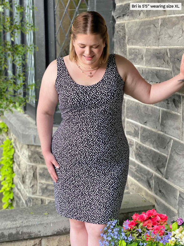 Miik model Bri (five feet five, xlarge) standing next to a brick wall looking down wearing Miik's Maryse reversible sweetheart dress in starry night print reversed 