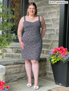 Miik model Bri (five feet five, xlarge) standing in front of a brick wall smiling wearing Miik's Maryse reversible sweetheart dress in starry night print