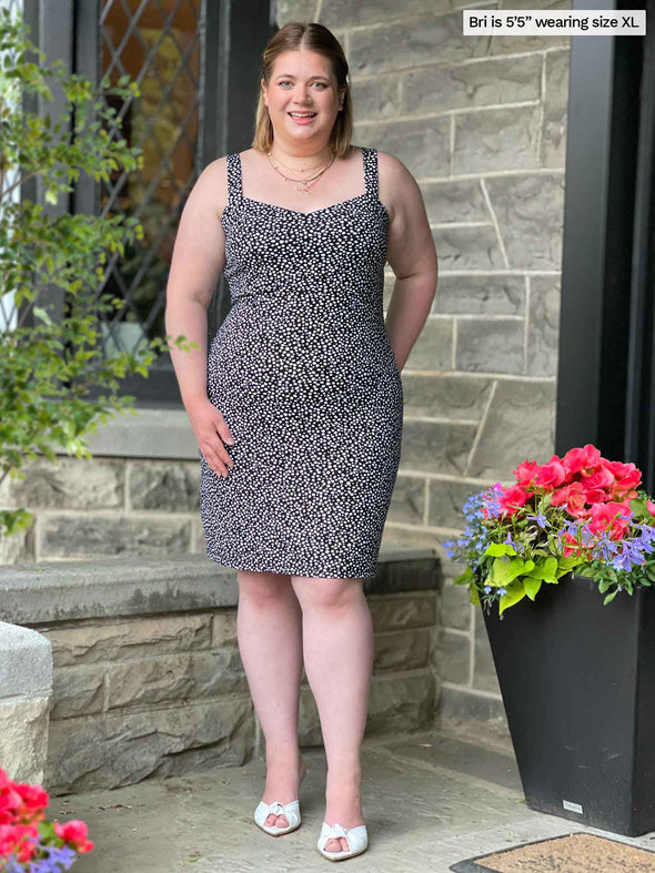 Miik model Bri (five feet five, xlarge) standing in front of a brick wall smiling wearing Miik's Maryse reversible sweetheart dress in starry night print