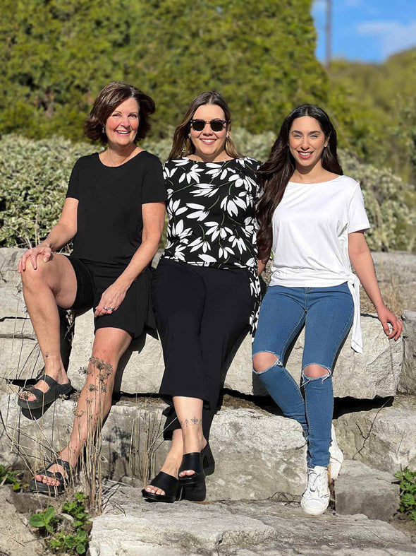 Miik founder Donna and models Christal and Yasmine sitting on a rock all wearing the same top: Melody side tie in black, white lily and white 