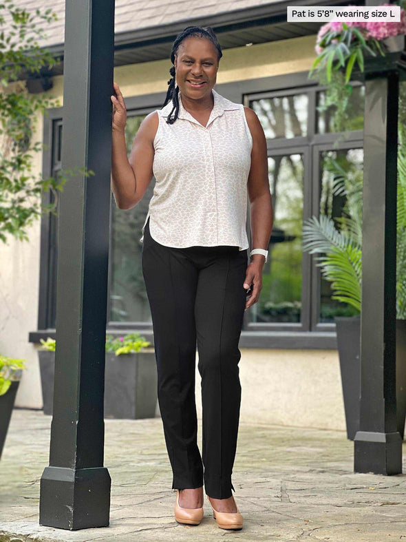 Miik model Pat (five feet eight, large) smiling wearing Miik's Mika sleeveless collared shirt in cobblestone print with a dressy black pant