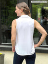 Miik model Johanna (five feet six, size xsmall) standing with her back towards the camera showing the back of Miik's Mika sleeveless collared shirt in white