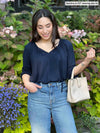 Woman standing in nature wearing Miik's Mitchel long sleeve boho blouse in navy with jeans.
