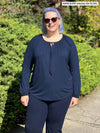 Woman standing in nature wearing Miik's Mitchel long sleeve boho blouse in navy with navy pants.