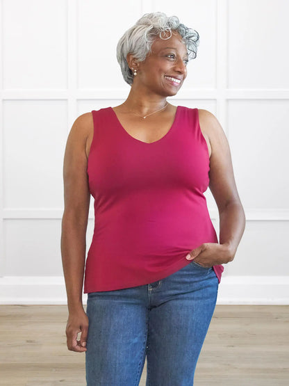 Woman wearing a pink tank top and blue jeans indoors.