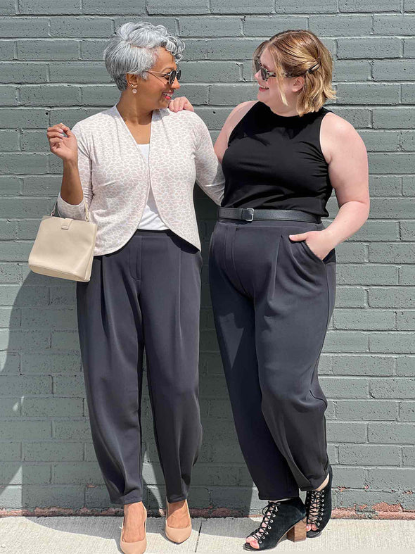 Miik models Keethai and Bri standing next to each other both wearing Miik's Nida pleat front tapered pant in graphite 