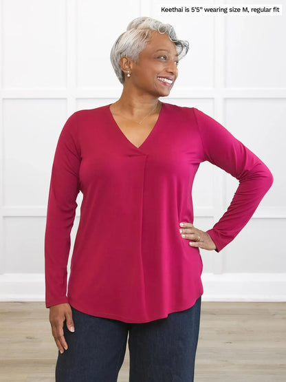 Woman wearing a red long-sleeve top with text indicating size and fit information. 