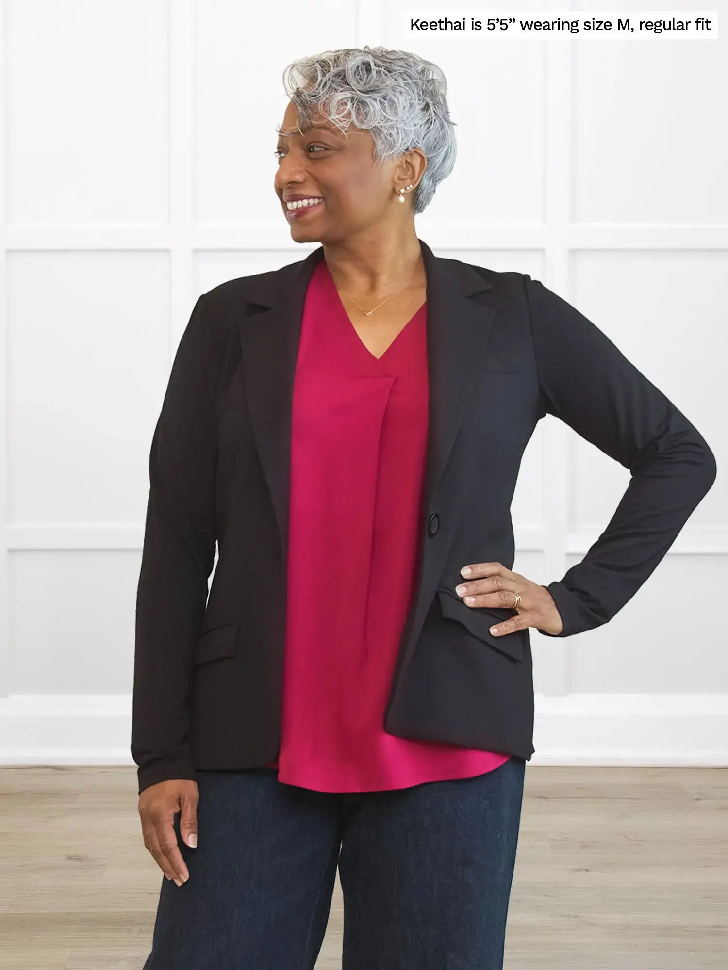 Woman wearing a black blazer over a red top with text indicating size and fit information. 