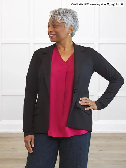 Woman wearing a black blazer over a red top with text indicating size and fit information. 