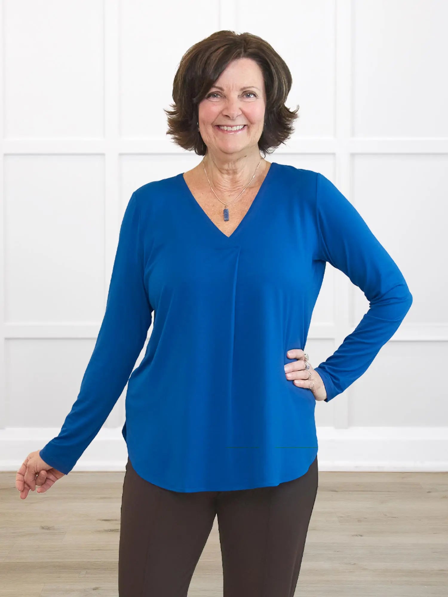 Woman wearing a blue long-sleeve top against a white background