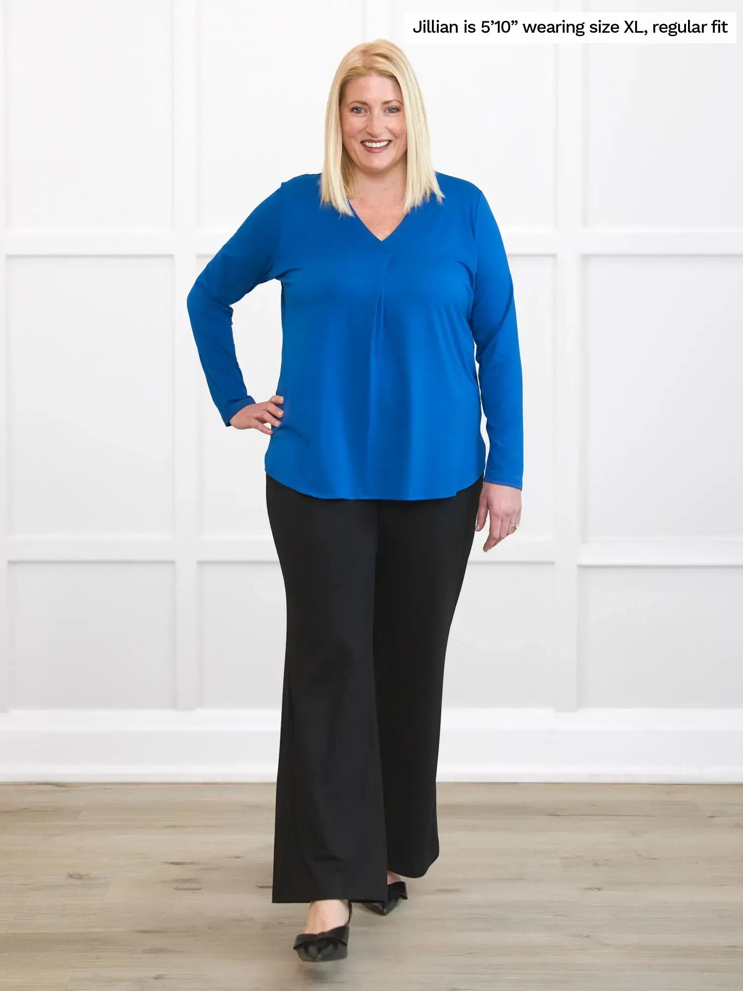 Woman wearing a blue top and black pants against a white background 