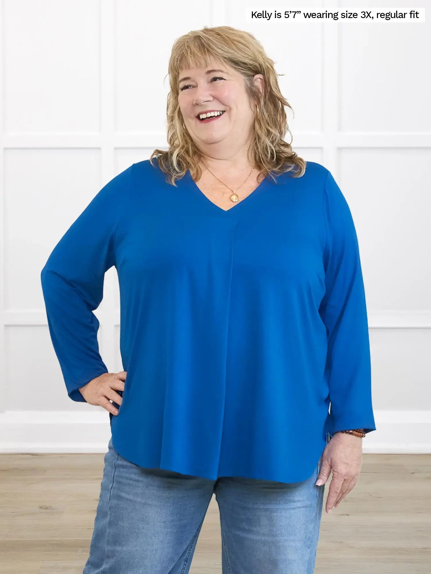 Woman wearing a blue top and jeans against a white background 