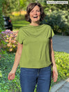 Miik founder Donna (5'6", small) laughing wearing Miik's Noah draped dolman top in green moss and jeans 