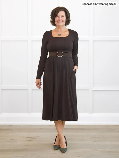 Woman wearing a brown dress with a belt in a white room 