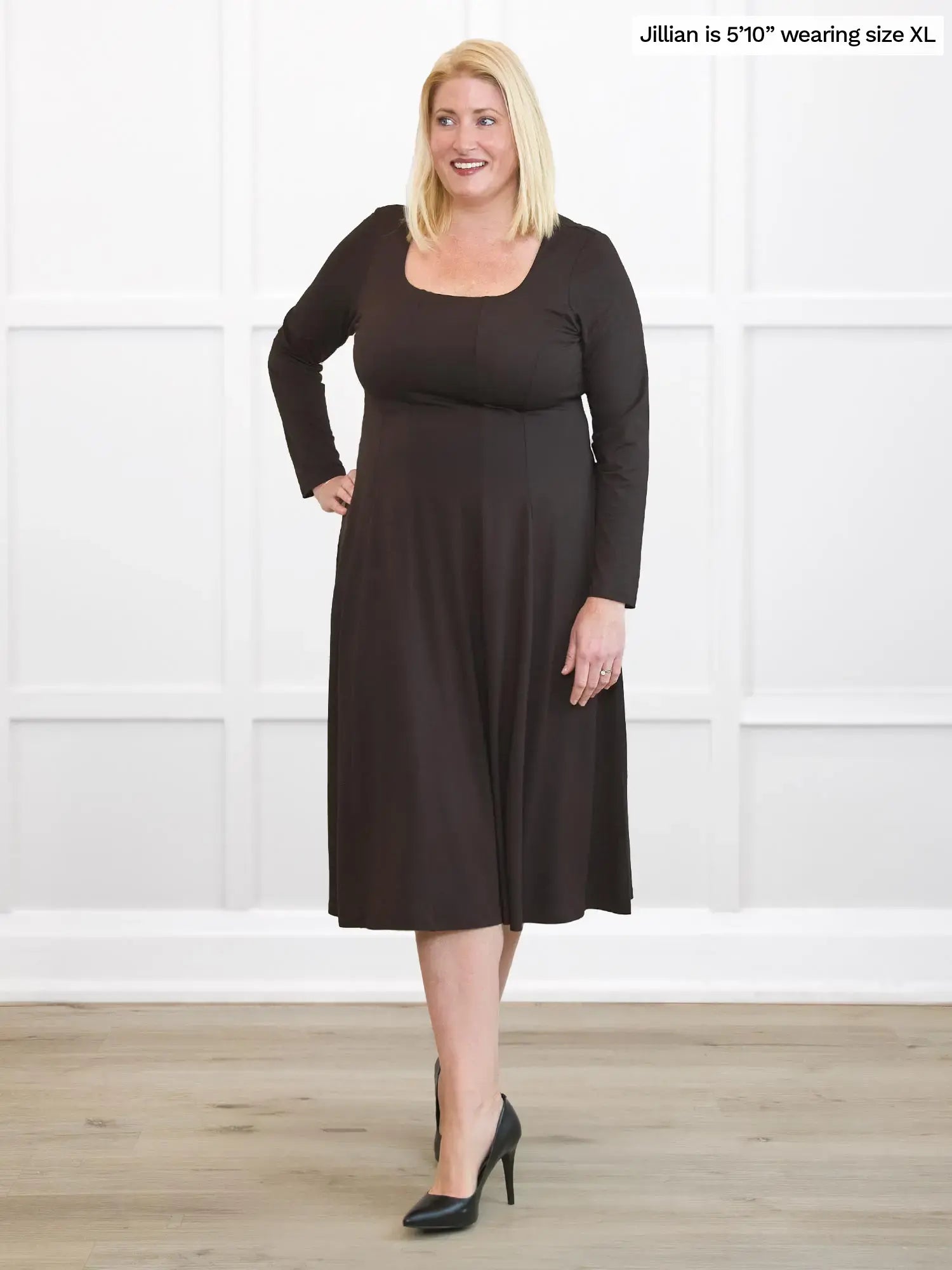Woman wearing a brown dress standing against a white background 