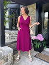 Miik founder Donna (five feet six, small) smiling while standing in a front house wearing Miik's RJ midi flounce dress with pockets in ruby