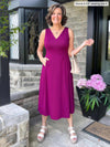 Miik founder Donna (five feet six, small) smiling while standing in a front house wearing Miik's RJ midi flounce dress with pockets in ruby