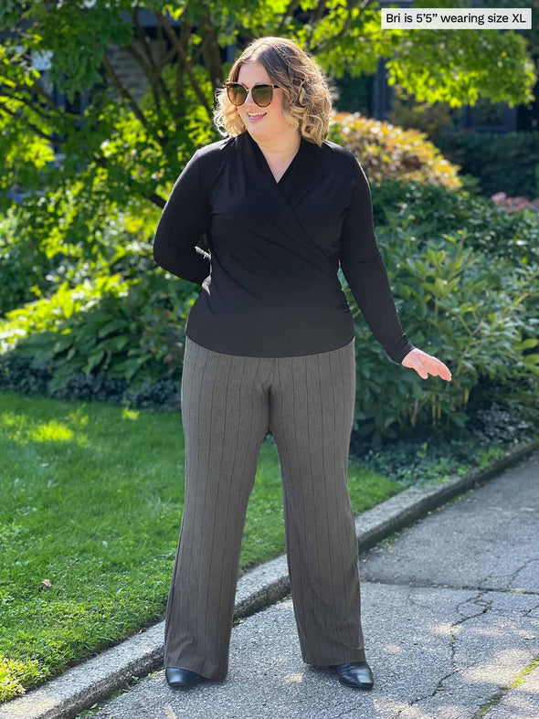 Miik model Bri (five feet five, xlarge) smiling and looking away wearing Miik's Reed high waisted pant with pockets in granite melange pinstripe with a black long sleeve top