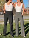Two women wearing Miik's Reed high waisted pant with pockets in charcoal pinstripe and granite wide pinstripe to show the difference between both colours