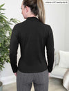 Miik model Johanna (five feet six, size xsmall) standing with her back towards the camera showing the back of Miik's Reni ruched faux-wrap blouse in black
